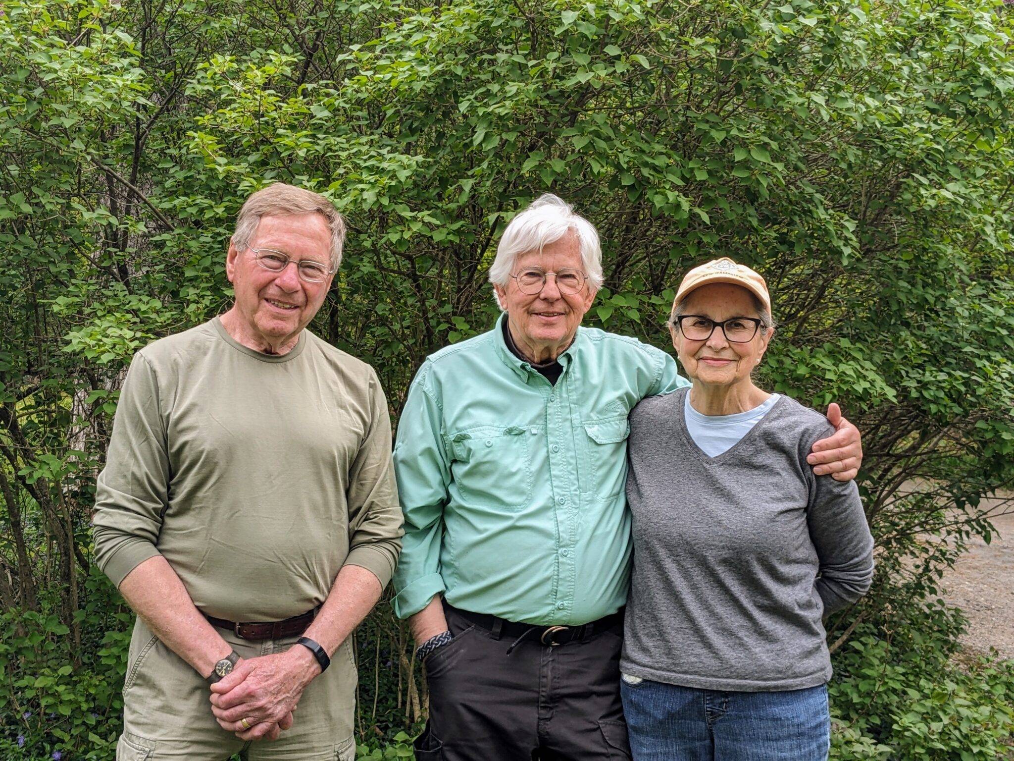 Elizabeth Gillette stands with husband Robert Gillette and brother-in-law Jay Kenty in front of a flowering bush at Thissell-Smith Memorial Forest in Ossipee, New Hampshire